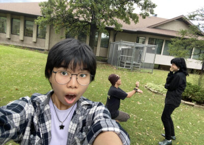 a photo of three friends, two of them proposing as a joke in the background whilst the third one is holding the camera looking shocked