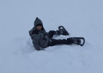 boy laying in snow wearing trail walking shoes